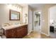 Bathroom featuring a vanity with brown cabinets and access to a walk-in closet with built in shelving at 7624 Russell Ct, Arvada, CO 80007