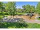 Playground with swings, slides, and climbing structure surrounded by grassy parkland and mature trees at 7624 Russell Ct, Arvada, CO 80007