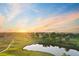 Aerial view of lush golf course with pond and scenic sunset, perfect for golfers and nature enthusiasts alike at 3090 W 107 Pl # F, Westminster, CO 80031