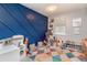 bedroom featuring stylish blue accent wall, colorful rug, window, and various toys at 4921 Beach Ct, Denver, CO 80221