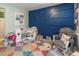 bedroom featuring stylish blue accent wall, colorful rug, rocking chair and various toys at 4921 Beach Ct, Denver, CO 80221
