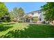 Picturesque backyard featuring lush greenery, mature trees, and a spacious covered patio at 2062 Hyacinth Rd, Highlands Ranch, CO 80129