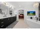 Modern bathroom featuring black and gold fixtures, double vanity, tub and chandelier at 2062 Hyacinth Rd, Highlands Ranch, CO 80129