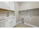 Well-lit laundry room with white cabinets, stainless steel sink, and functional shelving at 17196 W 92Nd Loop, Arvada, CO 80007