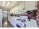 Galley kitchen with white appliances and brick accent at 4855 Dover St, Arvada, CO 80002