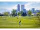 Scenic golf course view with a golfer teeing off, set against the backdrop of a city skyline and mountains at 1642 N Lafayette St # 2, Denver, CO 80218