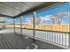 Covered back porch with wood floors, a white railing, and views of the fenced backyard at 6187 E 155Th Pl, Thornton, CO 80602
