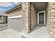 Side view of a stone clad home featuring a two-car garage and covered front porch at 6187 E 155Th Pl, Thornton, CO 80602