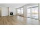 Spacious living room featuring light wood floors, a fireplace, large windows, and sliding glass doors at 6187 E 155Th Pl, Thornton, CO 80602