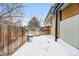 Side yard with wooden fence, trash can, and snowy ground at 6087 S Westview St, Littleton, CO 80120