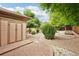 Charming backyard shed with brick pavers and gravel landscaping, set amongst mature trees and garden beds at 2069 Garrison St, Lakewood, CO 80215
