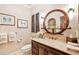Elegant bathroom featuring a wood vanity, round mirror, and decorative wall art at 2069 Garrison St, Lakewood, CO 80215