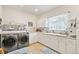 Bright laundry room with modern washer and dryer, white cabinets, and a large sink at 2069 Garrison St, Lakewood, CO 80215