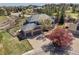 Aerial view of gray home with brick accents, lush landscaping, and spacious three-car garage at 404 Yarrow Pl, Castle Pines, CO 80108