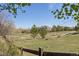 Scenic backyard view features an open meadow with a wooden fence and a glimpse of the home at 404 Yarrow Pl, Castle Pines, CO 80108