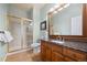 Bathroom featuring a glass-enclosed shower, wood vanity, granite countertop, and a large framed mirror at 404 Yarrow Pl, Castle Pines, CO 80108