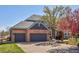 Attached three-car garage featuring dark gray doors and a concrete driveway at 404 Yarrow Pl, Castle Pines, CO 80108