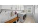 Modern laundry room equipped with white washer and dryer, wooden bench, and white cabinetry at 404 Yarrow Pl, Castle Pines, CO 80108