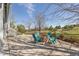 Outdoor patio with blue chairs surrounding a brick firepit, and a scenic view of the lawn and trees at 404 Yarrow Pl, Castle Pines, CO 80108