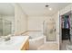Well-lit bathroom with a soaking tub, glass shower, wood vanity, and walk-in closet at 1767 N Pearl St # 308, Denver, CO 80203