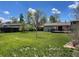 Picturesque backyard with mature trees, green grass, and a cozy wooden deck at 3062 S Florence Ct, Denver, CO 80231