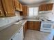 Kitchen with oak cabinets, white appliances, and tile flooring at 3062 S Florence Ct, Denver, CO 80231