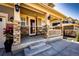 Inviting front porch with stone pillars, elegant lighting, and a charming entry perfect for relaxing at 7150 E 121St Pl, Thornton, CO 80602