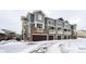 Gray townhouses with attached garages and snowy landscape at 9381 Ashbury Cir # 102, Parker, CO 80134