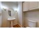 Elegant powder room featuring pedestal sink, decorative mirror, and sconce lighting above warm wood floors at 870 Homestake Ct, Castle Rock, CO 80108