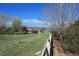 The serene backyard features a white fence, a lush grassy area, and mature trees, enhancing its natural beauty at 448 Winterthur Cir, Highlands Ranch, CO 80129