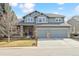 Charming two-story home showcasing a three-car garage, stone accents, and well-manicured lawn at 448 Winterthur Cir, Highlands Ranch, CO 80129