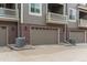 Attached garages featuring brick accents, carriage doors, and nearby air conditioning units at 9165 Kornbrust Dr, Lone Tree, CO 80124