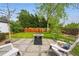 Serene backyard featuring a stone patio with a fire pit, surrounded by lush greenery and trees at 2626 Tennyson St, Denver, CO 80212