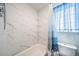 This bathroom shows a white tub with a white marbled tile surround and a shower curtain at 12565 Eudora St, Thornton, CO 80241