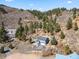 View of stunning hillside home with lush trees and winding driveway surrounded by rock outcroppings and natural landscape at 508 Viola St, Palmer Lake, CO 80133