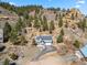 Beautiful exterior of hillside home with attached garage surrounded by lush trees and unique rock outcroppings at 508 Viola St, Palmer Lake, CO 80133