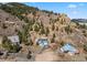 Aerial view of hillside home surrounded by mature trees and rock formations, with attached garage and winding driveway at 508 Viola St, Palmer Lake, CO 80133