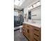 Stylish bathroom features a wood vanity, blue tiled shower, and modern lighting fixtures at 6470 Field St, Arvada, CO 80004