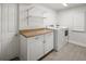 Bright laundry room with modern washer and dryer, storage cabinets, countertop, and vinyl flooring at 6470 Field St, Arvada, CO 80004