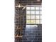 Close-up of the shower, featuring unique glass block window and brass fixtures at 6470 Field St, Arvada, CO 80004