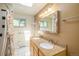 Bathroom featuring double sinks with granite countertops, updated lighting, and tiled flooring at 6780 Allison St, Arvada, CO 80004