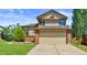 Front of home with tan siding and brick accents, with a large two car garage at 19937 E Loyola Pl, Aurora, CO 80013