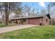 Brick ranch-style home featuring a well-maintained front yard and a modern garage door at 8750 W 8Th Ave, Lakewood, CO 80215