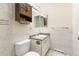 Well-lit bathroom features a white vanity, tile walls, and dark wood cabinet above toilet at 1250 S Monaco Pkwy # 67, Denver, CO 80224