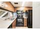 A kitchen featuring stairs through opening, tile backsplash, oven, microwave, cabinets, and refrigerator at 1250 S Monaco Pkwy # 67, Denver, CO 80224