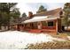 Charming home featuring a covered front porch and a brick chimney, surrounded by mature trees and a wintry landscape at 17720 Canterbury Dr, Monument, CO 80132