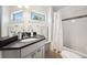 Bathroom featuring a sink with a black countertop, window and a shower with white subway tile at 2564 S Carey Way, Denver, CO 80222
