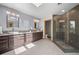 Modern bathroom featuring double sinks, tile floors, a skylight, and a glass-enclosed shower at 1423 Belford Ct, Evergreen, CO 80439
