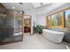 Luxurious bathroom with a glass shower, soaking tub, and heated towel rack next to an ensuite bedroom at 1423 Belford Ct, Evergreen, CO 80439
