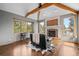 Well-lit living room with fireplace, wood floors, exposed beam, and large windows at 1423 Belford Ct, Evergreen, CO 80439